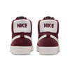 Back view of a pair of NIKE SB BLAZER MID BURGUNDY CRUSH / SUMMIT WHITE sneakers. The word "NIKE" is prominently displayed in maroon on the heel of each shoe.