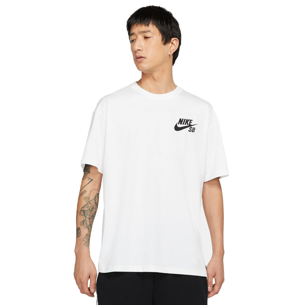 Person wearing a white short-sleeved NIKE SB LOGO SKATE TEE WHITE with black shorts, standing against a plain white background.