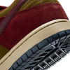 Close-up of the heel and outsole of the NIKE SB DUNK LOW PRO DARK TEAM RED / OLIVE FLAK by nike, showcasing a suede upper in Dark Team Red and Olive Flak with a beige midsole and black textured rubber outsole.