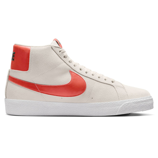 A Nike SB Blazer Mid Phantom / Cosmic Clay high-top sneaker with a white base and red detailing, designed for optimal board traction suitable for any skateboarder.