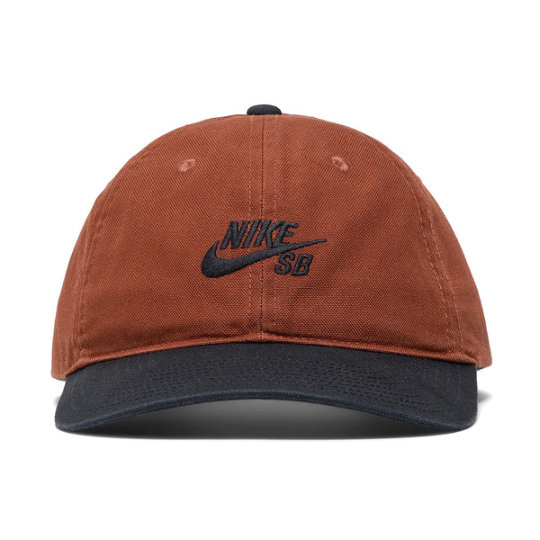 The NIKE SB CLUB HAT CINNAMON by Nike is a cotton twill cap in brown, featuring a black brim, black embroidered Nike SB logo on the front, and an adjustable back strap for a customizable fit.