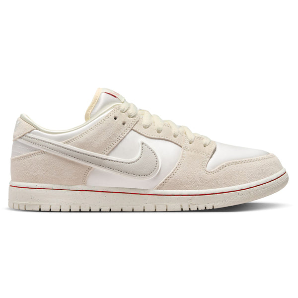 A beige and white low-top sneaker with a swoosh logo on the side, white laces, and a white sole with a red accent line, inspired by the nike NIKE SB 'CITY OF LOVE' DUNK LOW PRO WHITE / RED.