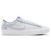 The NIKE SB BLAZER LOW PRO GT "20 YEARS" in Summit White/Game Royal showcases a sleek white sneaker design accented with blue piping, featuring the iconic white swoosh logo and a distinctive "20" emblem near the heel. Inspired by Grant Taylor, it provides enhanced comfort with Air Zoom cushioning, all set against a pristine white backdrop.