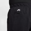 Close-up of a person wearing black Nike SB Kearny Cargo Skate Pants with a pocket and white Nike logo above the pocket. These lightweight, sweat-wicking pants offer a customizable fit for comfort on and off the skateboard.