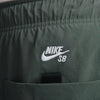 Close-up of vintage green fabric with a white embroidered "Nike" logo above a small black detail, showcasing the loose fit design of these premium SB Kearny Cargo Skate Pants.