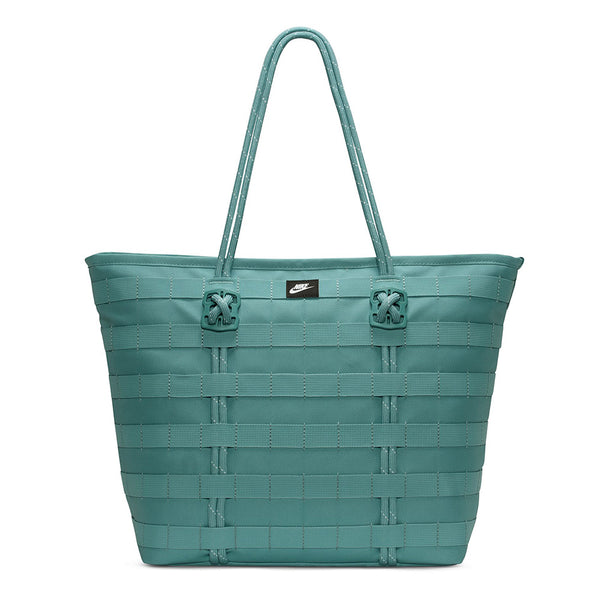 The NIKE RPM Tote (26L) in Denim Turquoise/Black/Summit White features two shoulder straps, a front black Nike logo tag, and is crafted from recycled polyester—ideal as a stylish laptop tote.