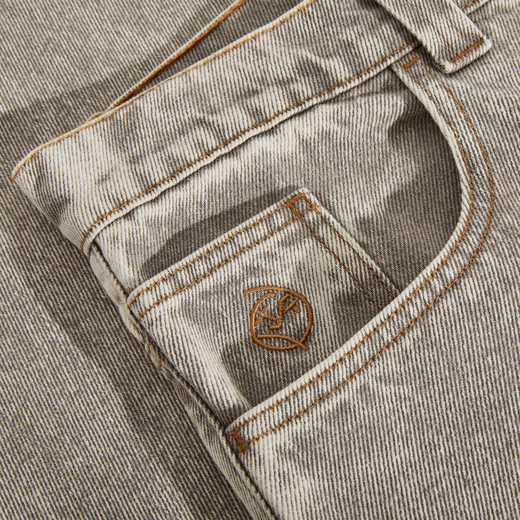 Close-up of acid beige denim fabric with visible texture and stitching, typical of POLAR jeans. A small, embroidered brown logo is featured on the front pocket.