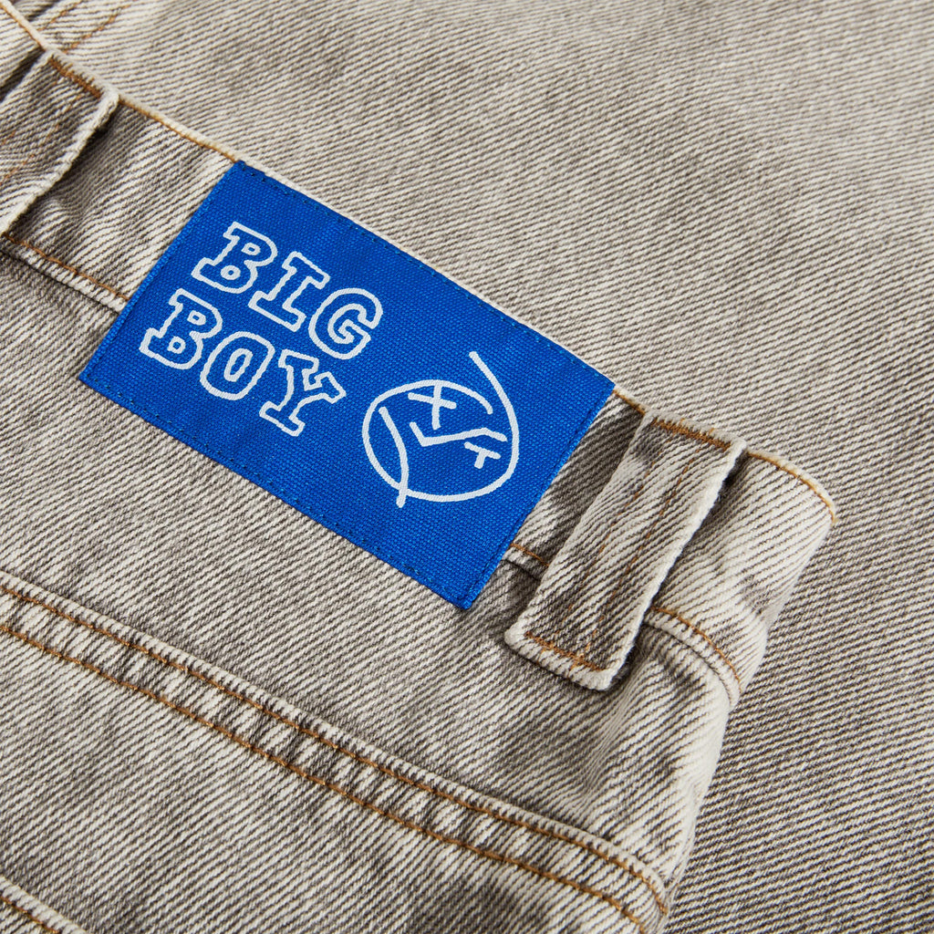 Close-up of denim fabric featuring an acid beige patch with the text "BIG BOY" alongside a graphic of a frowning face with crossed arms, highlighting the signature style of Polar Big Boy Jeans in a fashionable baggy fit.