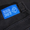 Close-up of the "POLAR BIG BOYS BROWN BLUE" label on a high-waisted pair of dark-colored jeans. The label also features a circular monogram design, emphasizing the 100% cotton denim fabric.