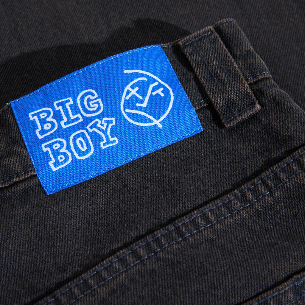 Close-up of the "POLAR BIG BOYS BROWN BLUE" label on a high-waisted pair of dark-colored jeans. The label also features a circular monogram design, emphasizing the 100% cotton denim fabric.