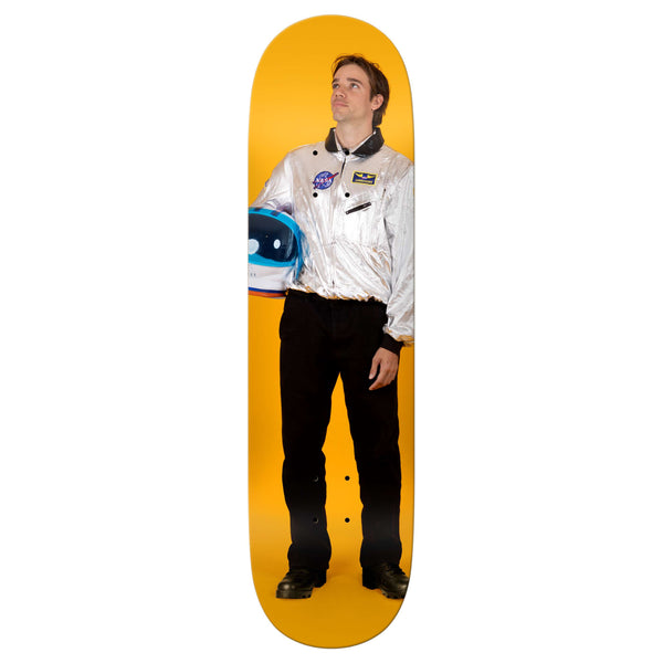 The REAL WILKINS ASTRONAUT skateboard features a man in a silver astronaut jacket with a blue and white helmet on a yellow background, printed on an 8.5" x 32.18" deck by REAL.