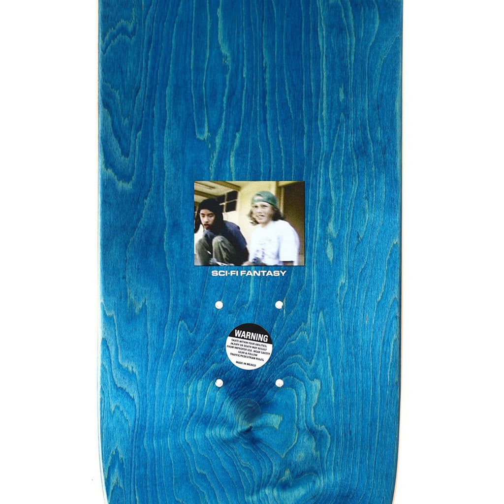 The SCI-FI FANTASY HSU BEAR SUIT skateboard deck features an image of two people in the center with the "SCI-FI FANTASY" text, paying homage to the BBS era. Below the image, there is a warning sticker.