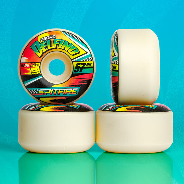 A set of four white SPITFIRE F4 DELFINO TURBO RADIALS 97D 57MM skateboard wheels, each featuring vibrant SPITFIRE F4 and Pedro Delfino branding, arranged against a blue background.