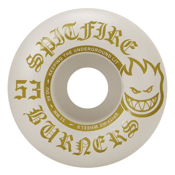 Gold and white design on a SPITFIRE F4 BURNERS 99D 53MM wheel featuring stylized text and an illustration of a flaming face.