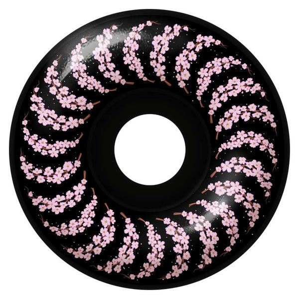 A 56mm black circular item with a central hole and adorned with a spiral pattern of pink cherry blossoms is called SPITFIRE F4 Yuto Cherry Blossom Classics 99D.