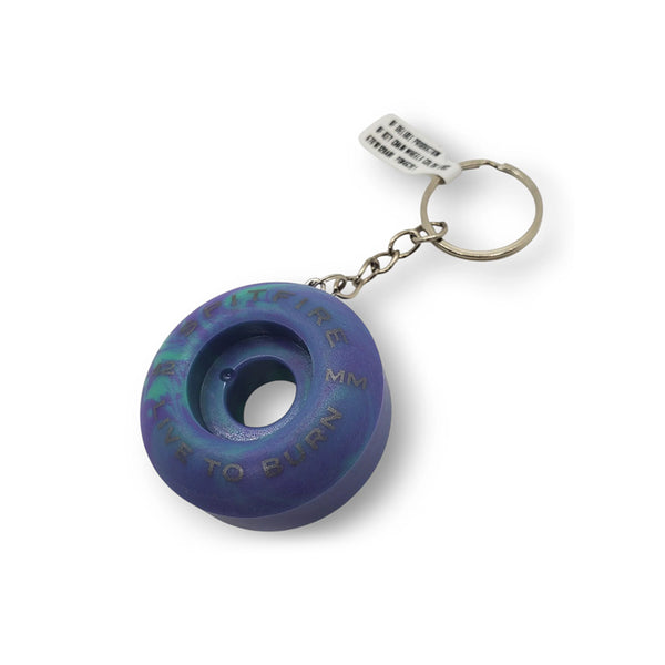 The SPITFIRE KEYCHAIN SWIRL PURPLE / TEAL features a metallic keychain with a purple and teal swirl 42mm skateboard wheel, engraved text, and a durable metal chain and keyring.