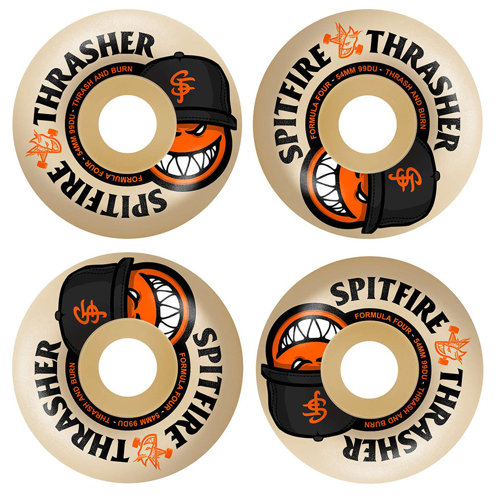 Four beige 54mm SPITFIRE X THRASHER F4 THE CITY RADIAL FULL 99D wheels feature a grinning cartoon face in a black cap with orange details, with “Spitfire Formula Four” and “Thrasher” text on the edge.