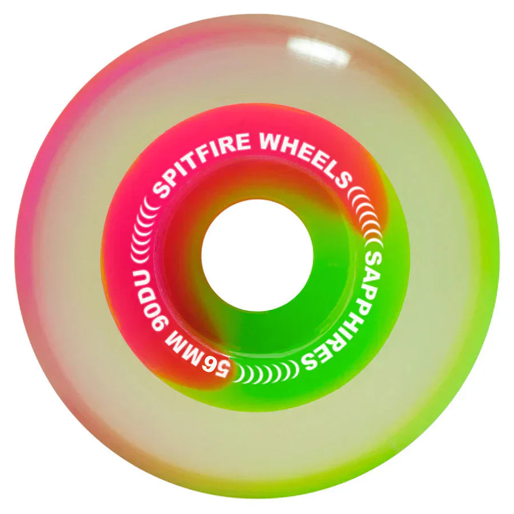 A neon-colored skateboard wheel with "SPITFIRE SAPPHIRES 90D 56MM PINK / GREEN" text printed on it, featuring the iconic Venom Script and blending pink, green, and white hues in a gradient pattern.