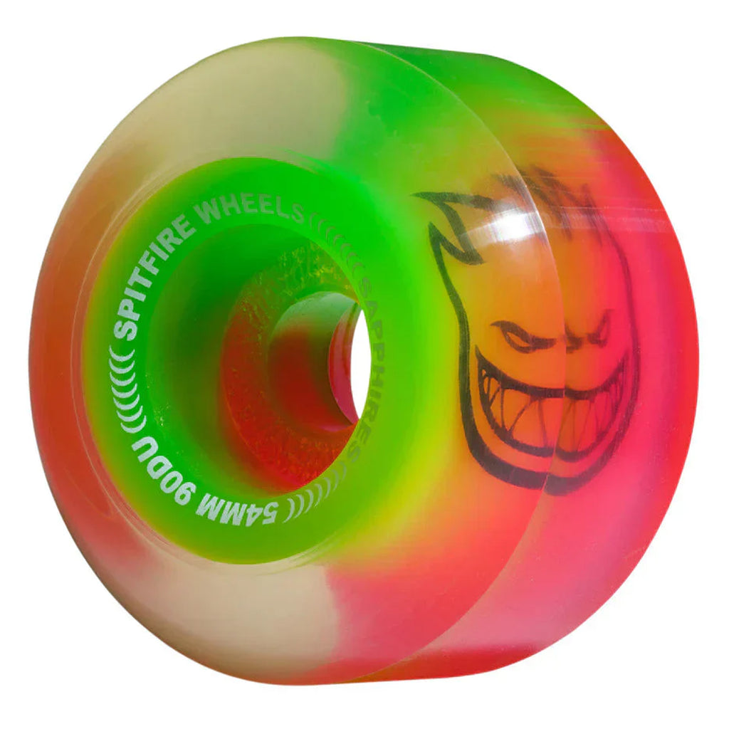 A colorful skateboard wheel with a blend of neon green, yellow, and pink hues features a grinning face graphic and the text "SPITFIRE SAPPHIRES 90D 56MM PINK / GREEN," "54MM 90DU," and "VENOM SCRIPT.