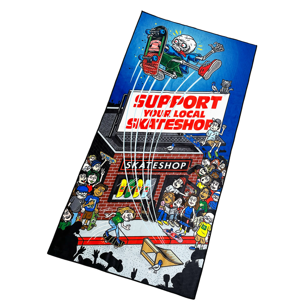 A vibrant SKATE SHOP DAY 2025 TOWEL by Bluetile Skateboards features a cartoon skateboarder performing a trick above a crowd, celebrating the event. It reads "Support Your Local Skate Shop" with an illustration of Todd Bratturd's shop in the background.