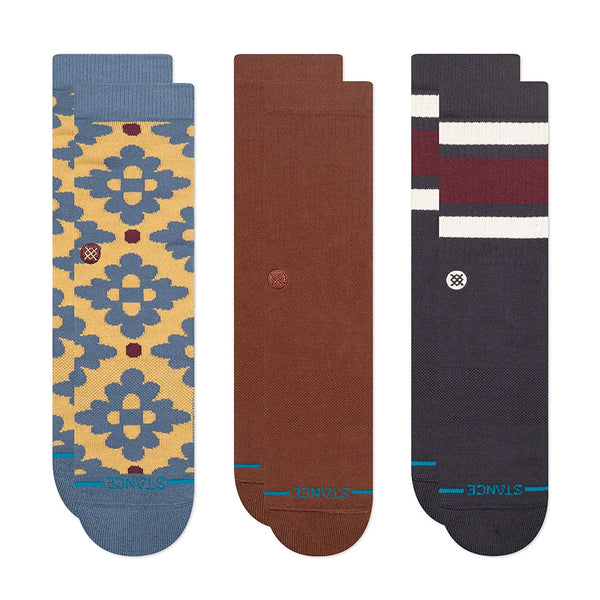The STANCE SOCKS CERAMIC 3 PACK INDIGO LARGE includes three pairs—yellow and blue geometric, solid brown, and dark with maroon and white stripes—in a soft cotton blend for all-day comfort.