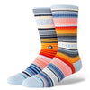 Two multi-colored, striped STANCE socks with various patterns. These large STANCE SOCKS CURREN ST ICE BLUE display a mix of blue, orange, red, and white tones, featuring horizontal stripes and geometric shapes.