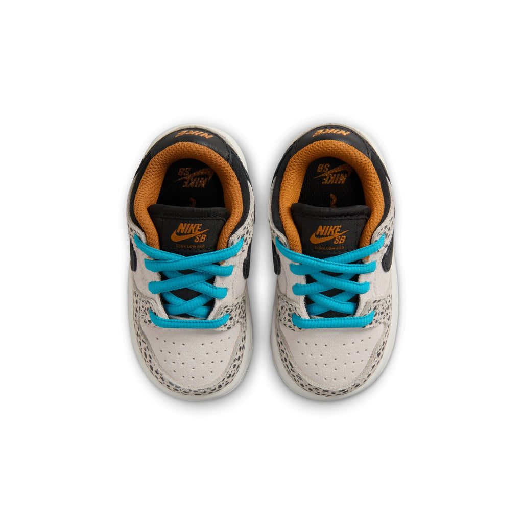 A pair of gray NIKE SB Dunk Low Pro Electric TD Phantom/Black toddler shoes with blue laces and orange inner lining, viewed from above, perfect for future skaters from Bluetile Skateboards.