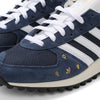 A pair of blue and gold ADIDAS X POP TRADING CO. TRX VINTAGE NAVY/WHITE sneakers by ADIDAS.