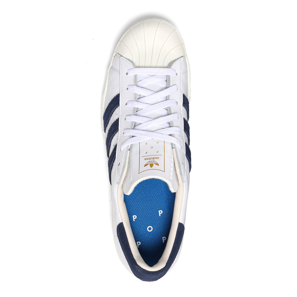 A white and blue ADIDAS X POP TRADING CO. SUPERSTAR ADV WHITE/NAVY sneaker.