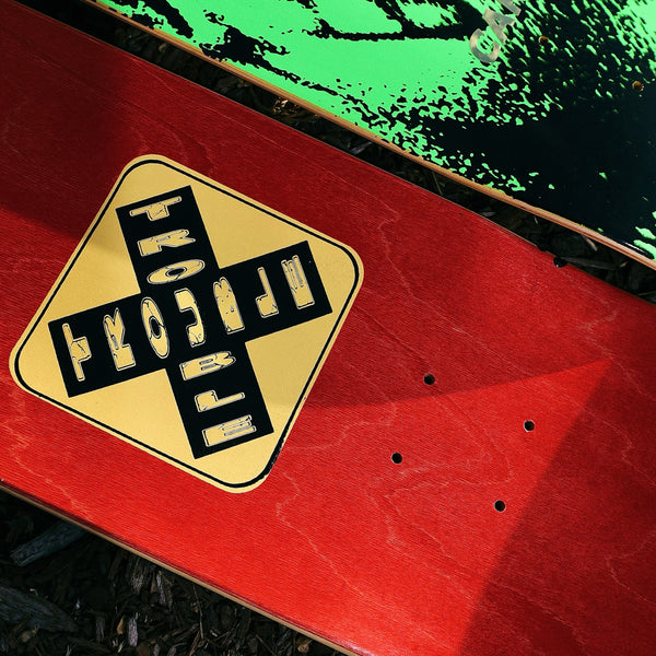 A Carpet Co. Trouble skateboard with base colors of red and green.