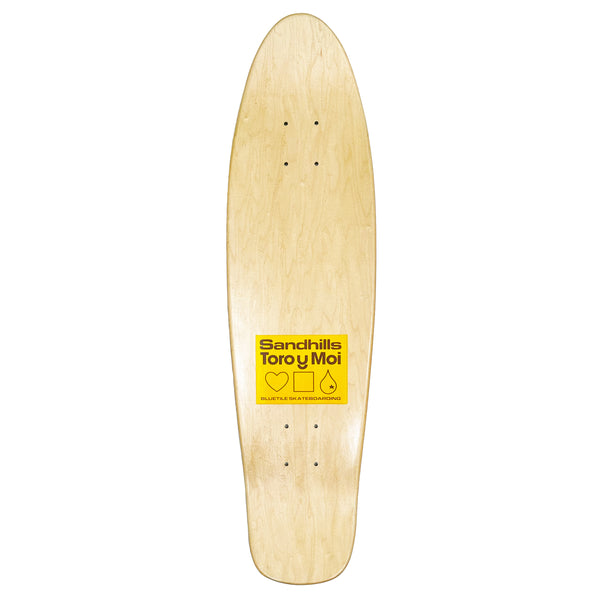 A TORO Y MOI X BLUETILE "SANDHILLS" CRUISER DECK skateboard with a yellow sticker on it.