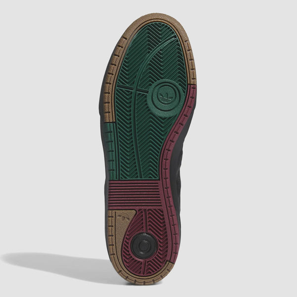 The image shows the sole of an ADIDAS TYSHAWN 2 BLACK / BLACK / GUM skateboarding shoe with an intricate pattern. The sole is colored in green, red, brown, and black, featuring various textures and ridges. Designed in collaboration with Tyshawn Jones, these shoes combine style and functionality for skateboarders.