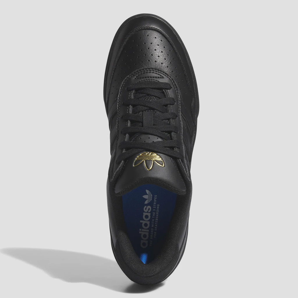 A top view of the ADIDAS TYSHAWN 2 BLACK / BLACK / GUM sneaker featuring laces, perforations on the toe box, and a gold Adidas logo on the tongue. The interior is blue with the brand name. Perfectly blending style and function, these skateboarding shoes embody Tyshawn Jones' signature flair.