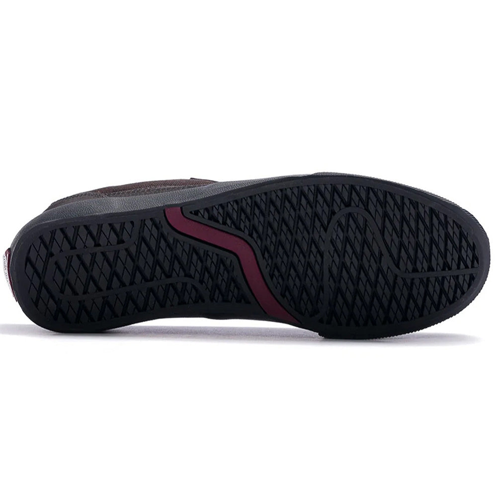 The image shows the black rubber sole of a VANS SKATE CURREN CAPLES DARK BROWN shoe with a red curved accent, DURACAP reinforcement, and a textured grip pattern.