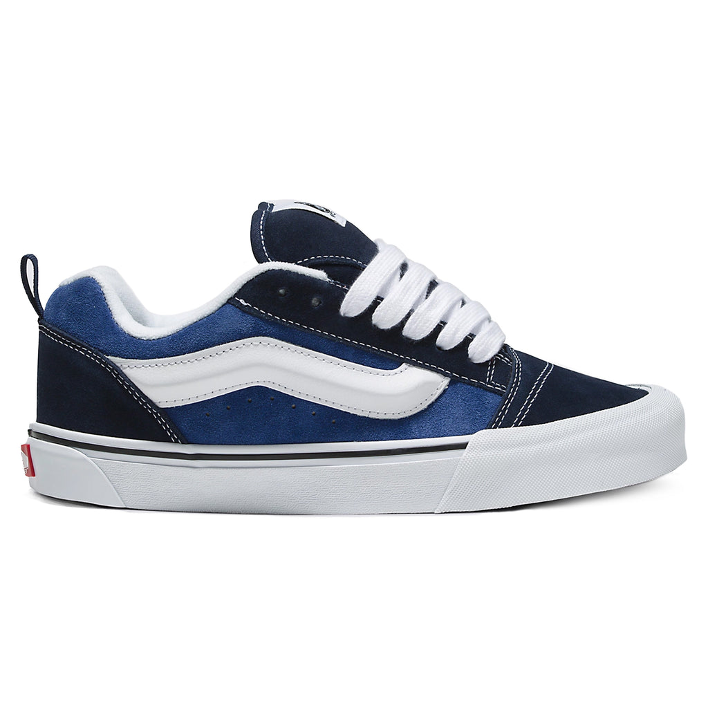 A VANS KNU SKOOL NAVY / TRUE WHITE sneaker with a white stripe along the side, white laces, and a white sole with black accents captures the essence of 90s style sneakers. These VANS kicks feature suede uppers, making them both stylish and durable.