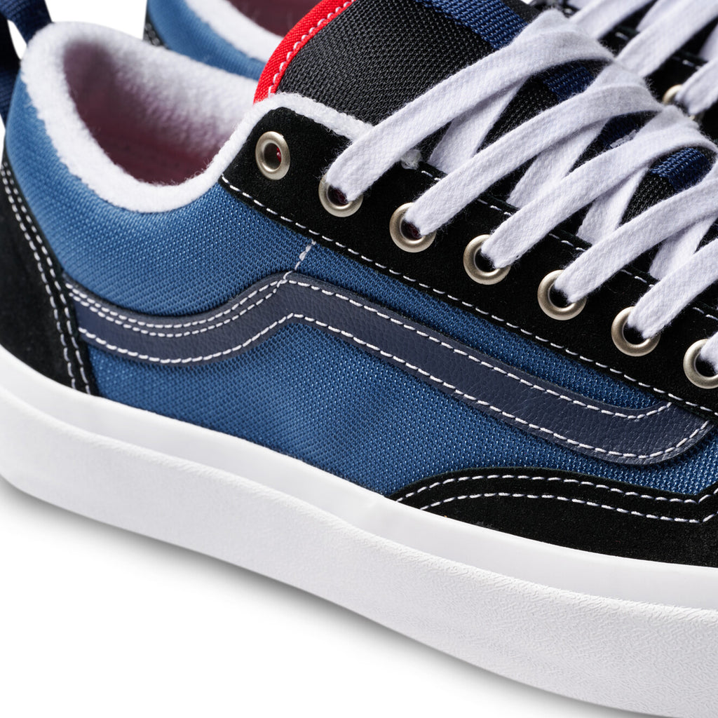 Close-up of a VANS SKATE OLD SKOOL 36+ sneaker, featuring navy and red color with white laces, stitching, metal eyelets, and a red interior lining. Enhanced with Vans DURACAP for durability.