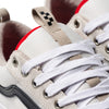 Close-up of VANS SKATE OLD SKOOL 36+ ANTIQUE WHITE / BLACK sneakers featuring beige laces, a black stripe, and a tongue with a beige pull tab adorned with black squares. Red lining inside the shoes showcases DURACAP technology for a stylish, durable design.