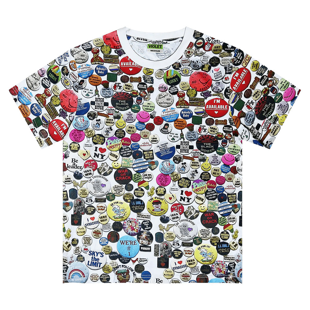 The violet VIOLET PINS TEE is a short-sleeved, 100% cotton T-shirt with a vibrant graphic of colorful buttons and badges featuring unique slogans, faces, and designs.