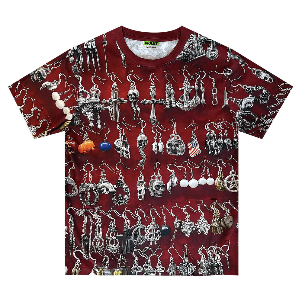The violet VIOLET ST.MARK'S EARINGS TEE is a red 100% cotton graphic t-shirt with an all-over print of silver and black earrings—skulls, crosses, and assorted designs—for a bold statement.