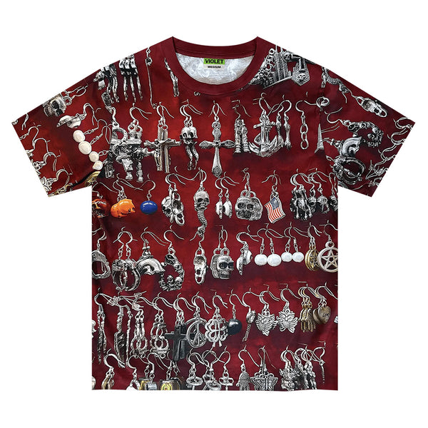 The violet VIOLET ST.MARK'S EARINGS TEE is a red 100% cotton graphic t-shirt with an all-over print of silver and black earrings—skulls, crosses, and assorted designs—for a bold statement.
