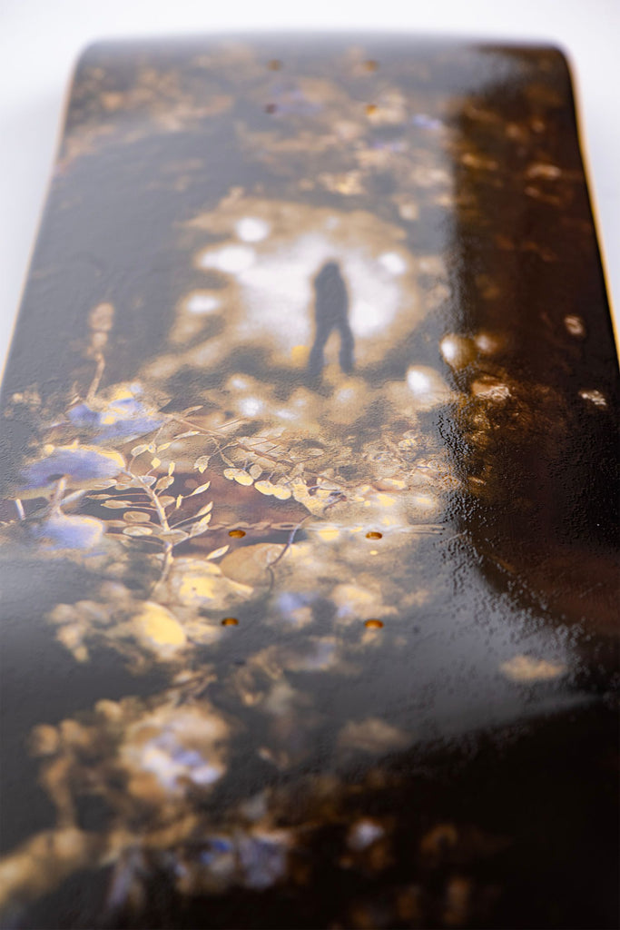 A LIMOSINE skateboard with a reflection of a person.