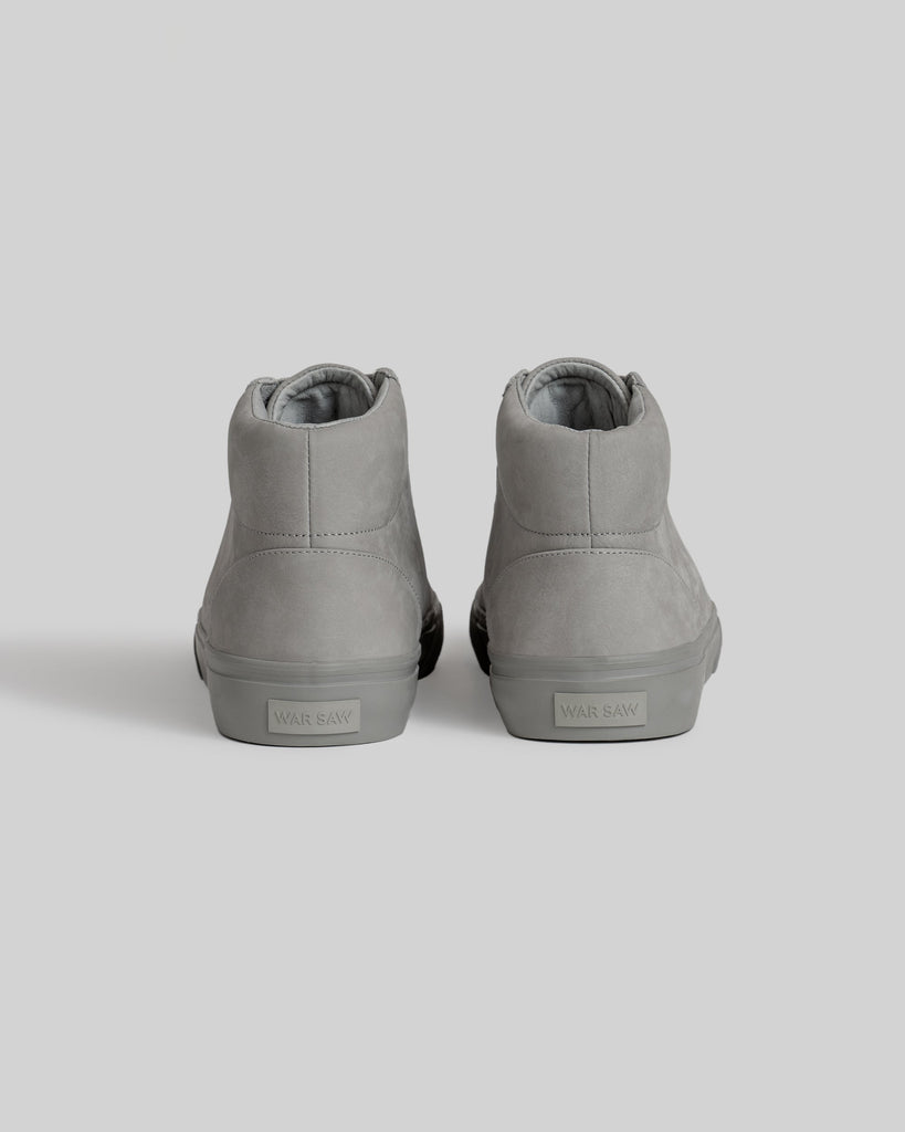 A pair of light gray CHAPTER MID | STONE FG NUBUCK high-tops by WARSAW LTD, viewed from the back with "WARSAW" on each heel—skate-inspired sneakers designed for style and comfort.