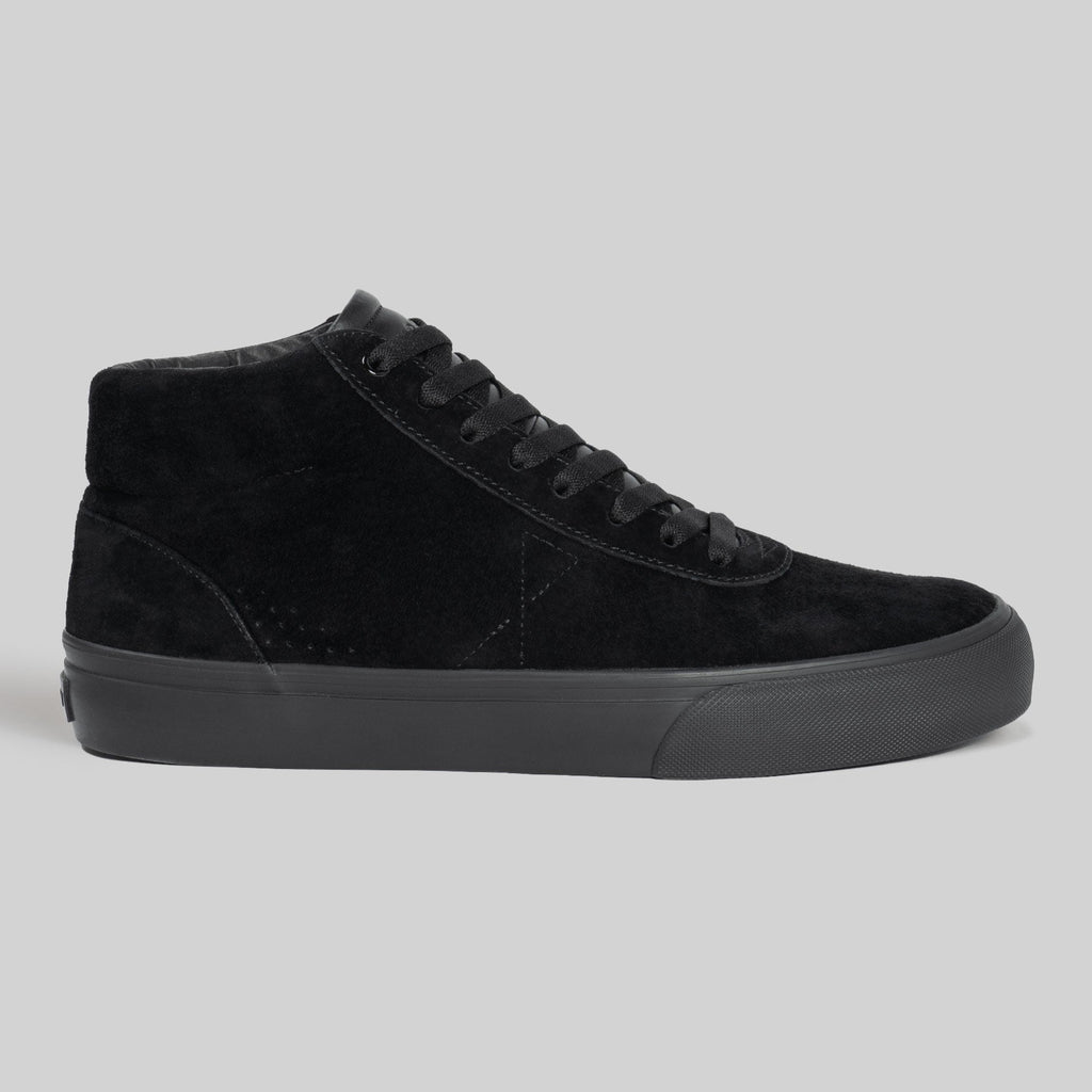 The CHAPTER MID | BLACK / BLACK by WARSAW LTD is a black pig suede high-top sneaker with black laces and a black rubber sole, shown in profile against a plain gray background. Designed for comfort and durability.