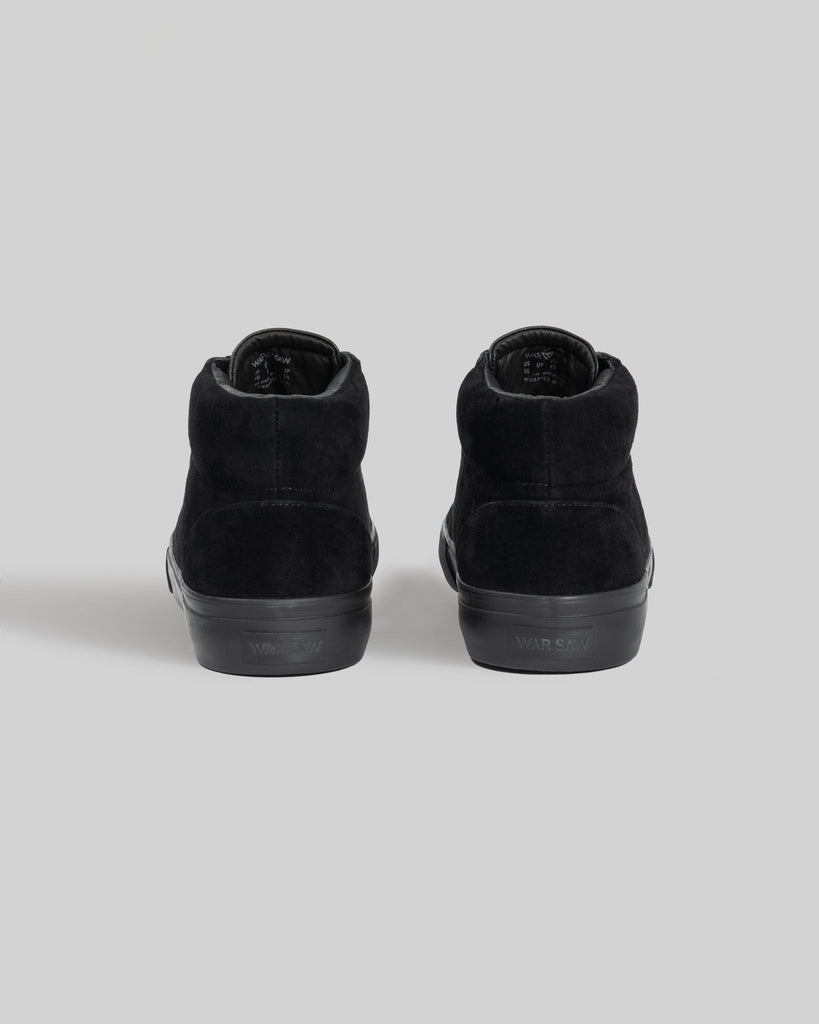A pair of WARSAW LTD CHAPTER MID | BLACK / BLACK pig suede high-top sneakers, shown from the back against a plain gray background, designed for comfort and durability.