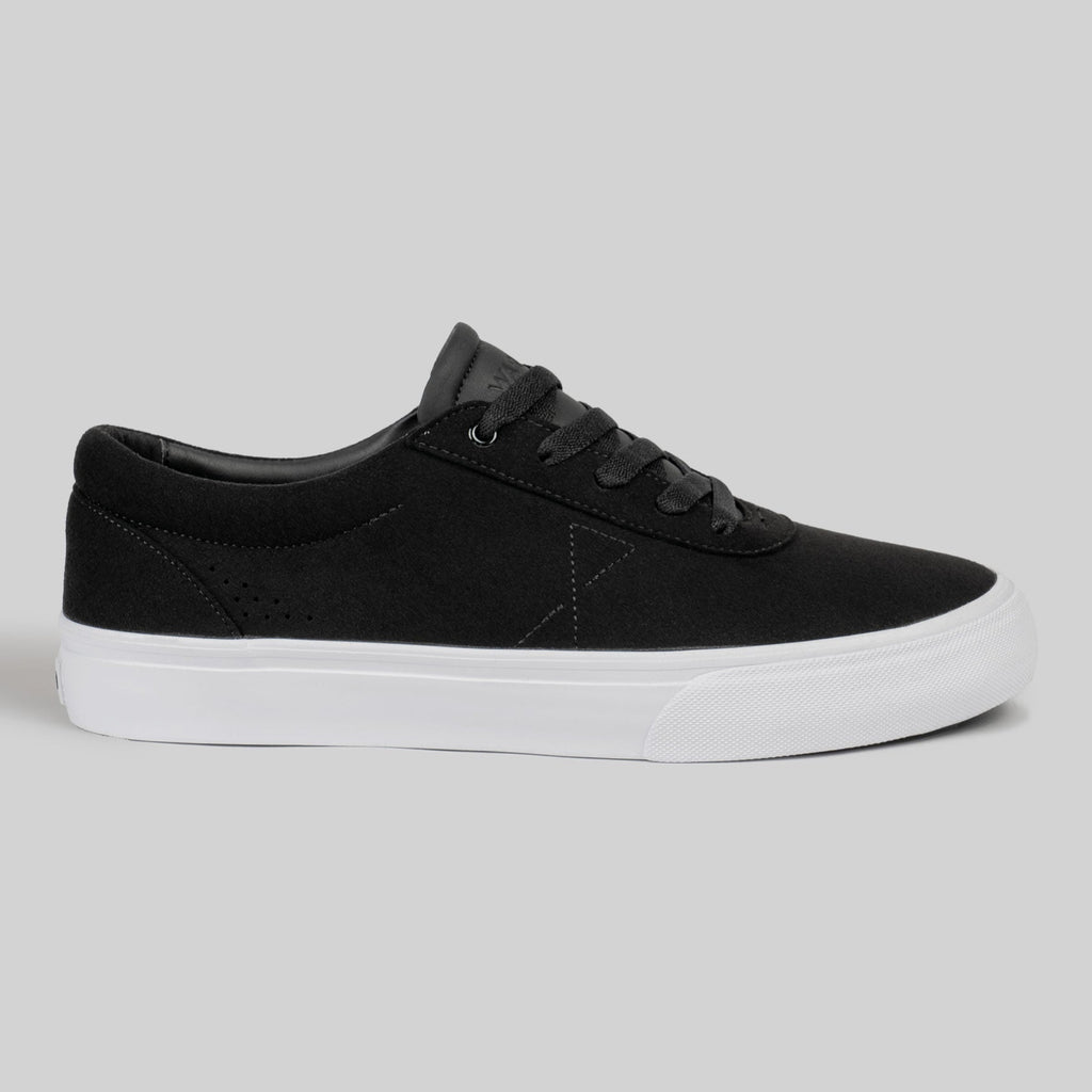 The CHAPTER | BLACK / WHITE SYNTHETIC by WARSAW LTD is a black low-top sneaker featuring synthetic material, black laces, and a white rubber sole, displayed in side profile against a plain gray background.