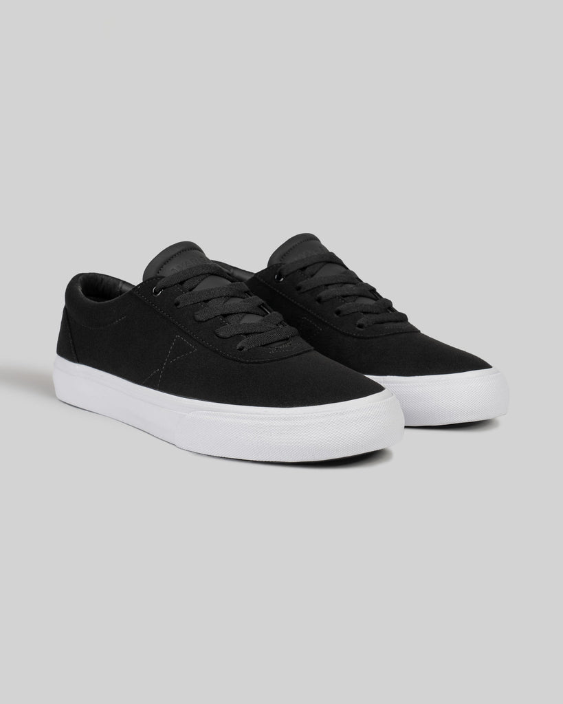A pair of CHAPTER | BLACK / WHITE SYNTHETIC low-top sneakers by WARSAW LTD, featuring a black synthetic upper and white rubber soles, displayed on a light gray background.