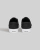 A pair of CHAPTER black and white synthetic sneakers by WARSAW LTD, skate-inspired with white soles, shown from the back and featuring "WAR SAW" on the heel tabs.