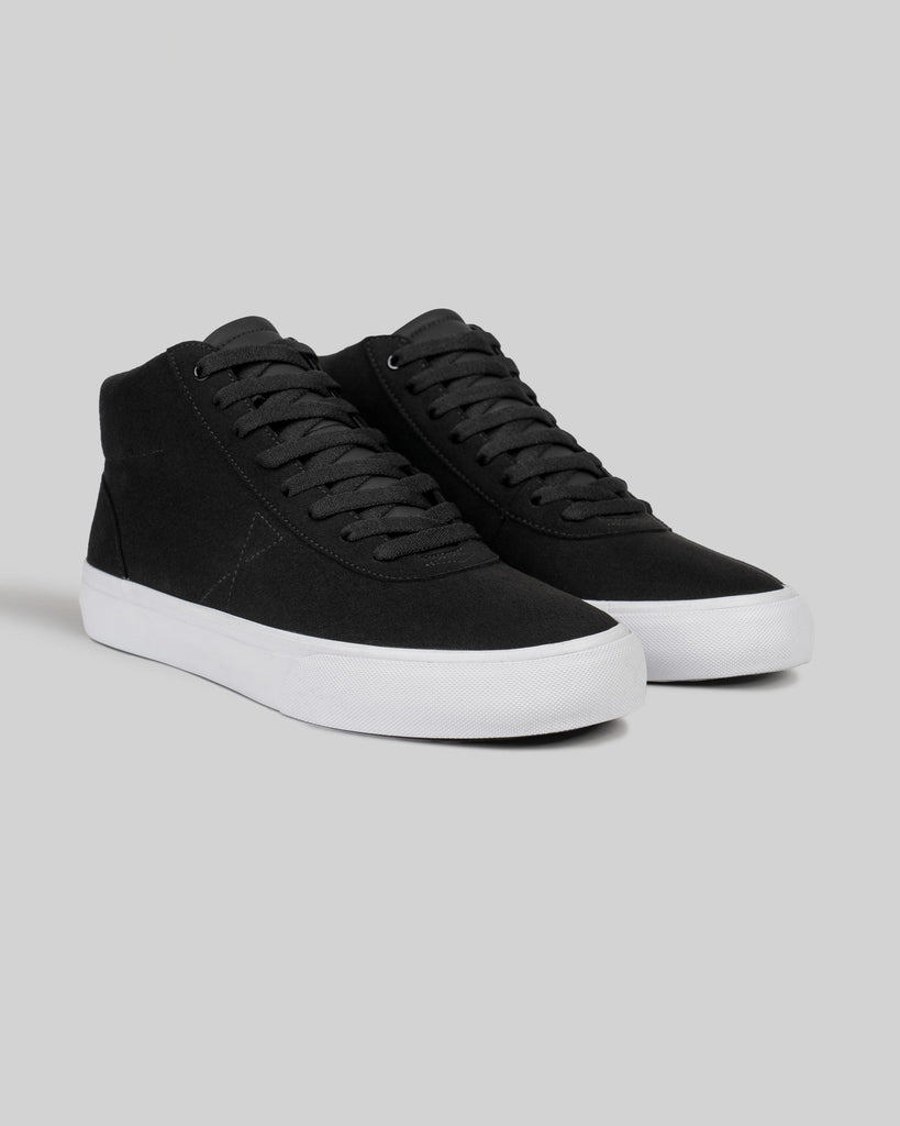 A pair of WARSAW LTD CHAPTER MID high-top sneakers in black synthetic suede with white rubber soles and black laces, displayed on a plain light gray background.