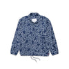 The HERSCHEL X KEITH HARING VOYAGE COACH by HERSCHEL is a navy blue jacket featuring white Keith Haring-inspired abstract line art, long sleeves, a collar, front buttons, and an adjustable drawstring hem.