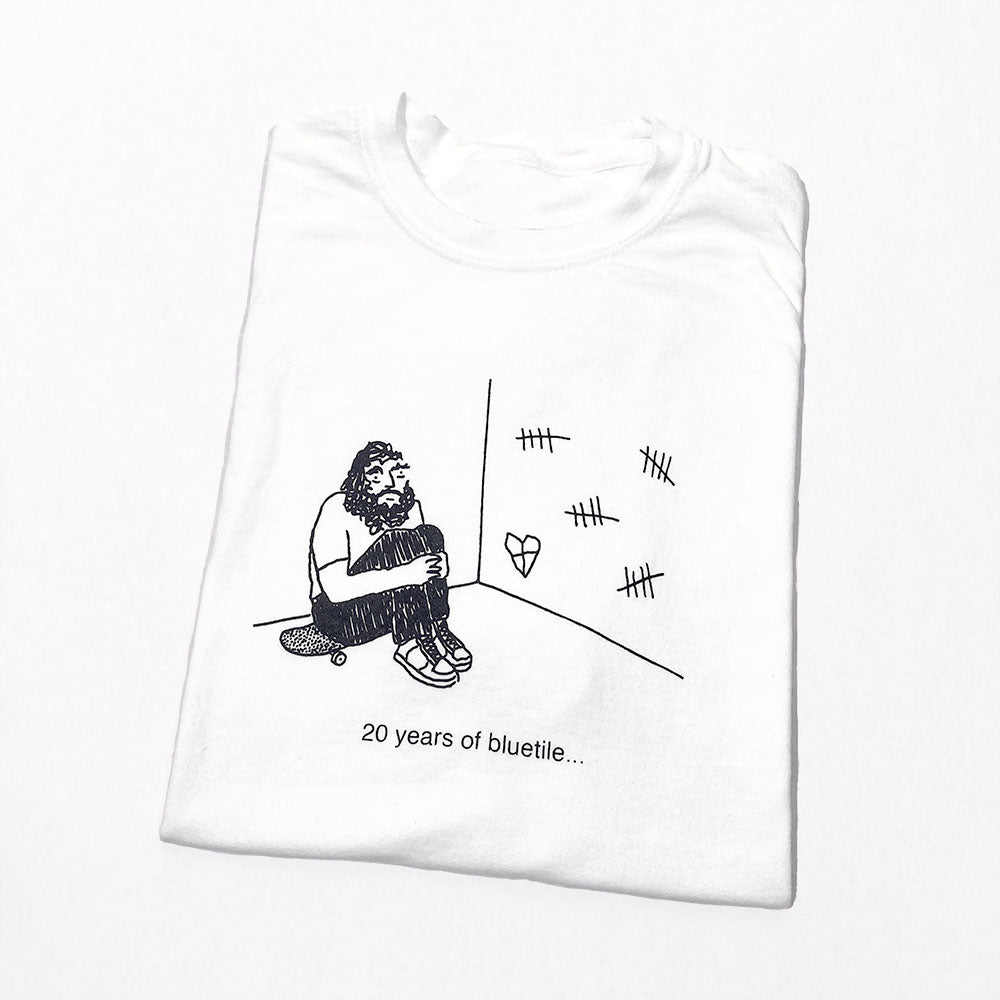 A BLUETILE 20 YEARS SAVA TEE WHITE with a drawing of a monkey designed by SAVA K. DESIGN, made by Bluetile Skateboards.